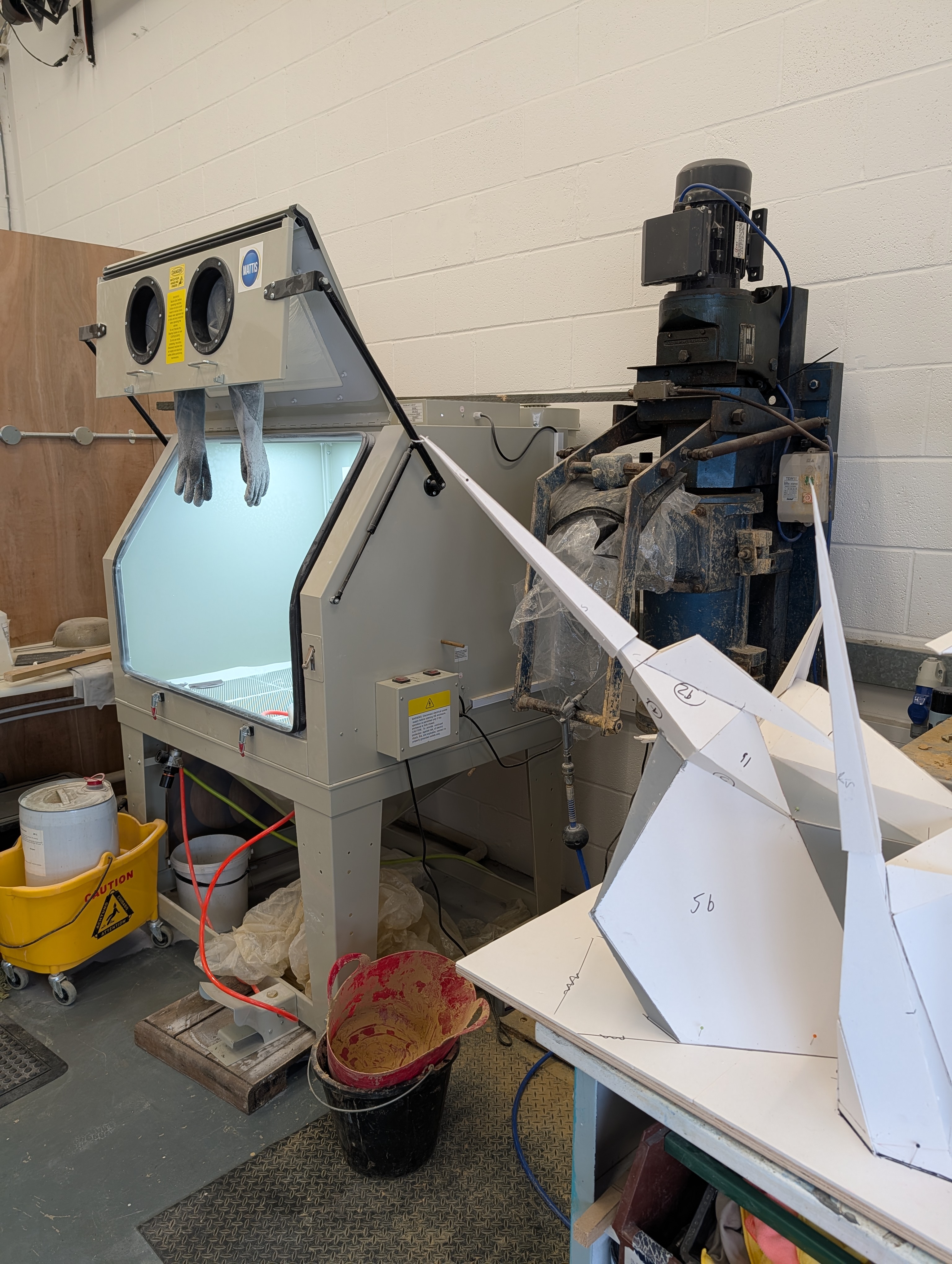 The sandblasting cabinet — one of several finishing tools in the workshop, with 3D-printed enclosure pieces visible